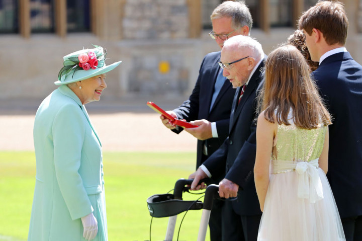 Sang Ratu, 94, yang hadir dalam upacara mengenakan mantel rok berwarna biru tua dan topi yang serasi, menganugerahi Moore sebagai seorang ksatria kerajaan dengan menggunakan pedang milik ayahnya, Raja George VI. 
