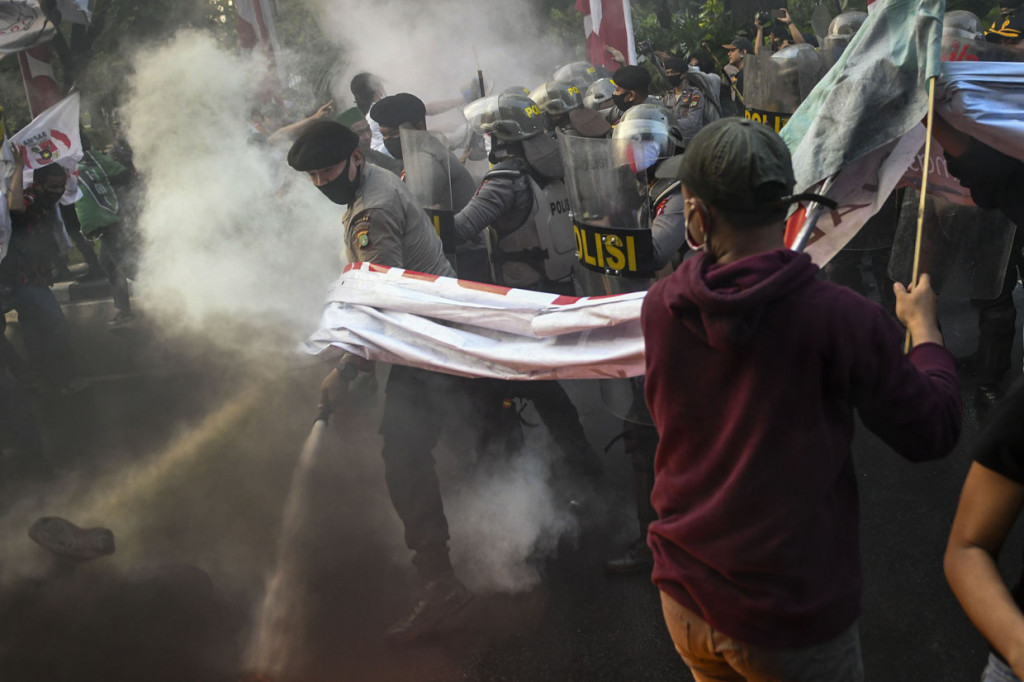 Anggota kepolisian berusaha memadamkan api yang membakar ban saat aksi mahasiswa di depan Balaikota Jakarta.