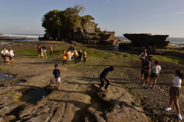 Wisatawan domestik menikmati pemandangan saat liburan Iduladha 1441H di masa Adaptasi Kebiasaan Baru tahap II di objek wisata Tanah Lot, Tabanan, Bali, Sabtu, 1 Agustus 2020. 