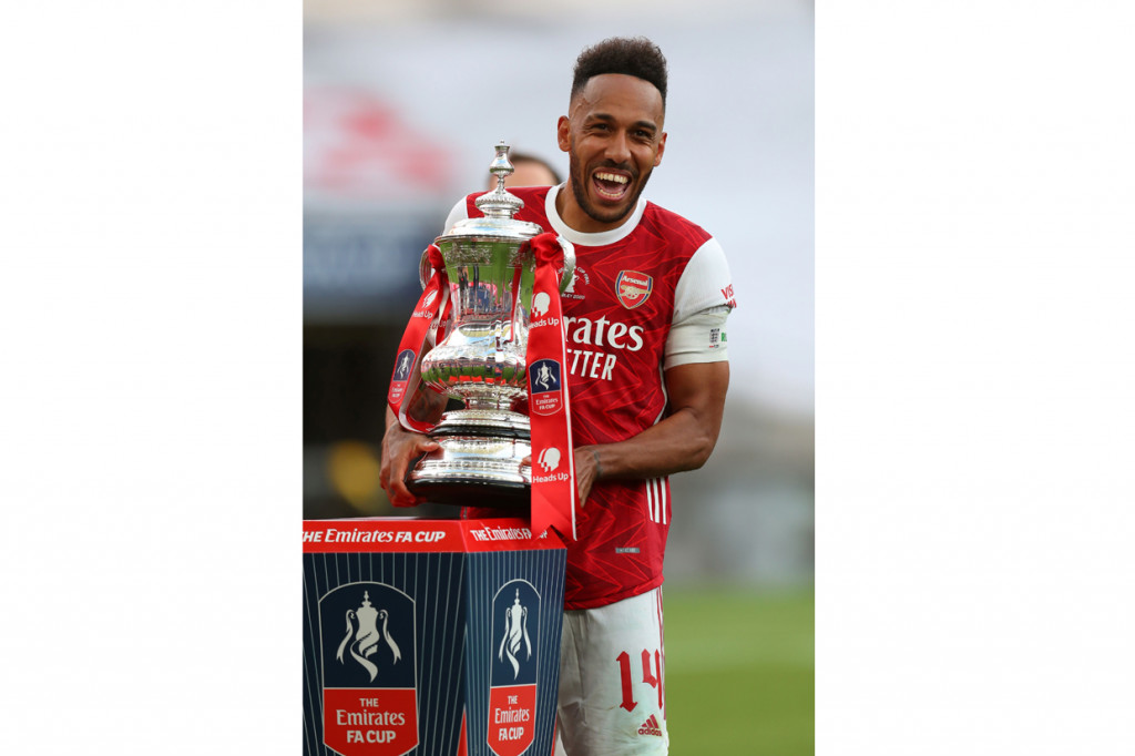 Pemain asal Gabon tersebut mengambil trofi Piala FA dari podium dan membawanya untuk diangkat bersama rekan setimnya yang sudah berbaris menunggunya. AFP Photo/Cathrtine Ivill