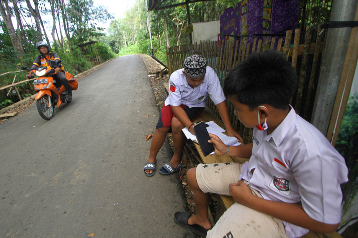 Sejumlah siswa mengikuti proses belajar mengajar dalam jaringan (daring) di bekas posko covid-19 di tepi jalan untuk mendapatkan sinyal jaringan internet, di Desa Madang, Kabupaten Hulu Sungai Selatan, Kalimantan Selatan, Selasa, 4 Agustus 2020. ANTARA FOTO/Bayu Pratama S