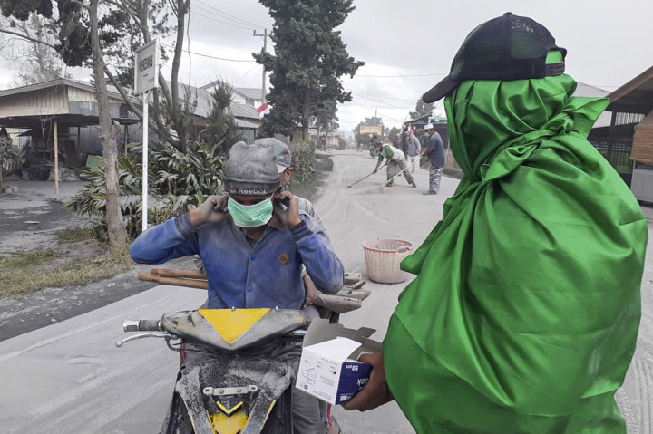 Warga membagikan masker kepada pengendara saat erupsi Gunung Sinabung di Karo, Sumatera Utara.