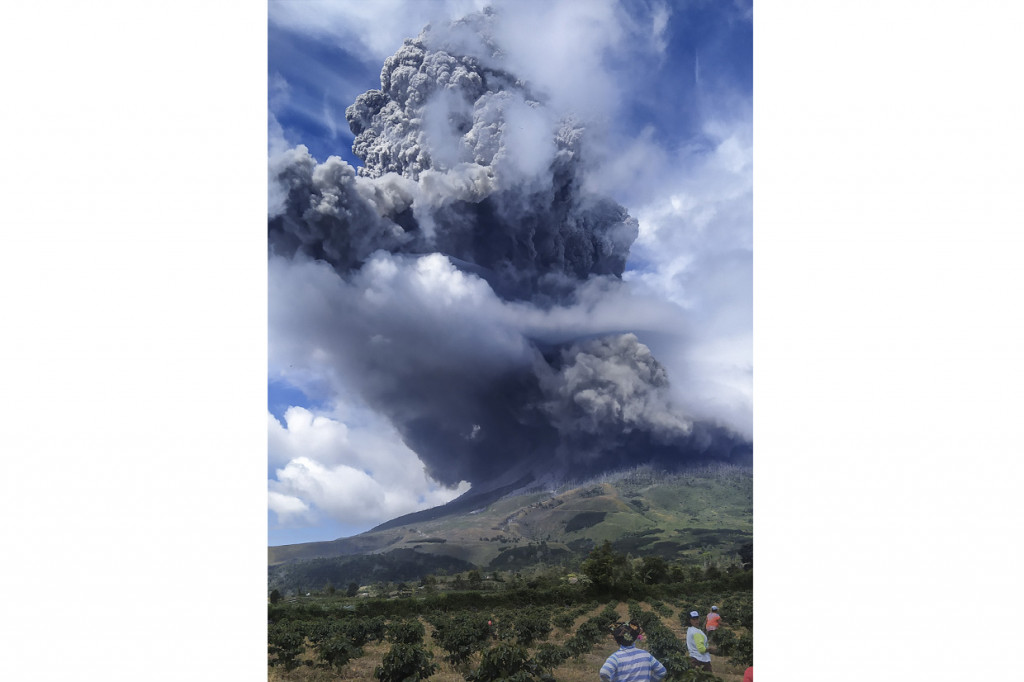 Warga mengamati Gunung Sinabung menyemburkan material vulkanik saat erupsi di Karo, Sumatera Utara.