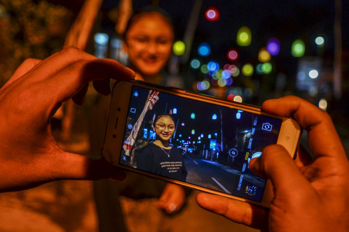 Warga berswafoto dengan latar belakang lampu lampion di Lembur Situ, Kabupaten Ciamis, Jawa Barat.
