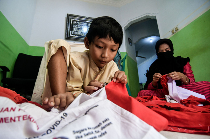 Warga sedang membongkar tas sembako banpres di jalan Caringin, Bedahan Barat, Sawangan, Depok, Jawa Barat.