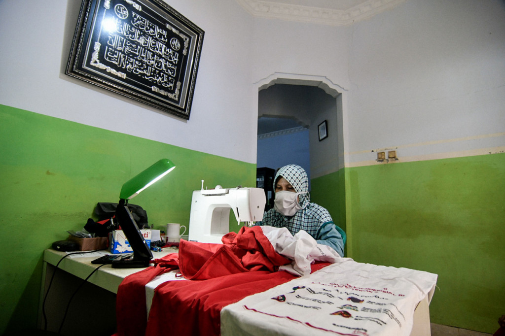 Warga sedang menjahit umbul-umbul merah putih di jalan Caringin, Bedahan Barat, Sawangan, Depok, Jawa Barat.