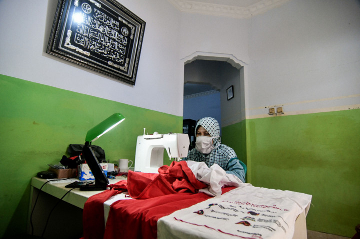 Warga sedang menjahit umbul-umbul merah putih di jalan Caringin, Bedahan Barat, Sawangan, Depok, Jawa Barat.