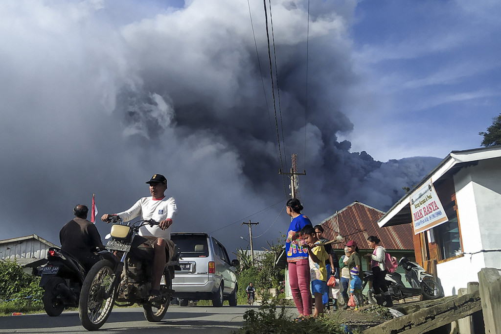 Sejumlah pengendara melintas di Jalan Karo-Langkat dengan latar belakang Gunung Sinabung yang menyemburkan material vulkanik di Desa Kutarayat, Naman Teran, Karo, Sumatera Utara, Kamis, 13 Agustus 2020.