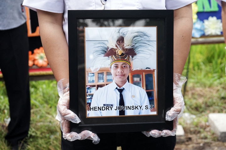 Petugas membawa foto staf KPU Yakuhimo, Papua almarhum Hendry Jovinsky saat proses pemakaman di Rewulu Wetan, Sidokarto, Godean, Sleman, Yogyakarta, Kamis, 13 Agustus 2020. 