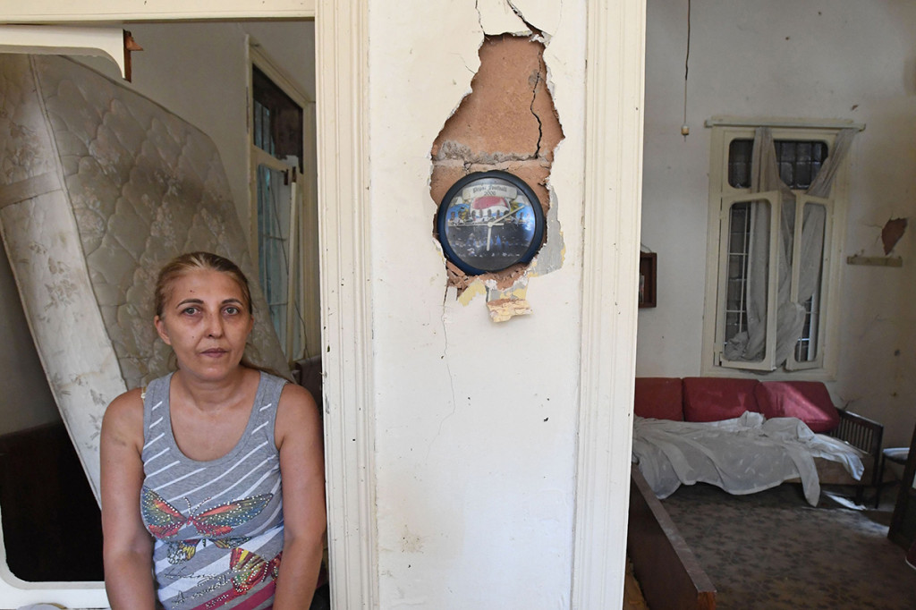 Seorang perempuan Lebanon duduk di samping jam yang berhenti berdetak pada pukul 06.07 di apartemennya yang rusak akibat ledakan di pelabuhan Beirut.