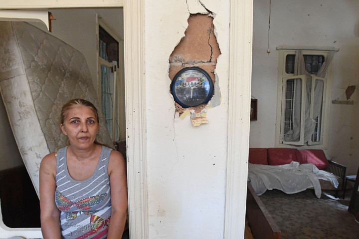 Seorang perempuan Lebanon duduk di samping jam yang berhenti berdetak pada pukul 06.07 di apartemennya yang rusak akibat ledakan di pelabuhan Beirut.