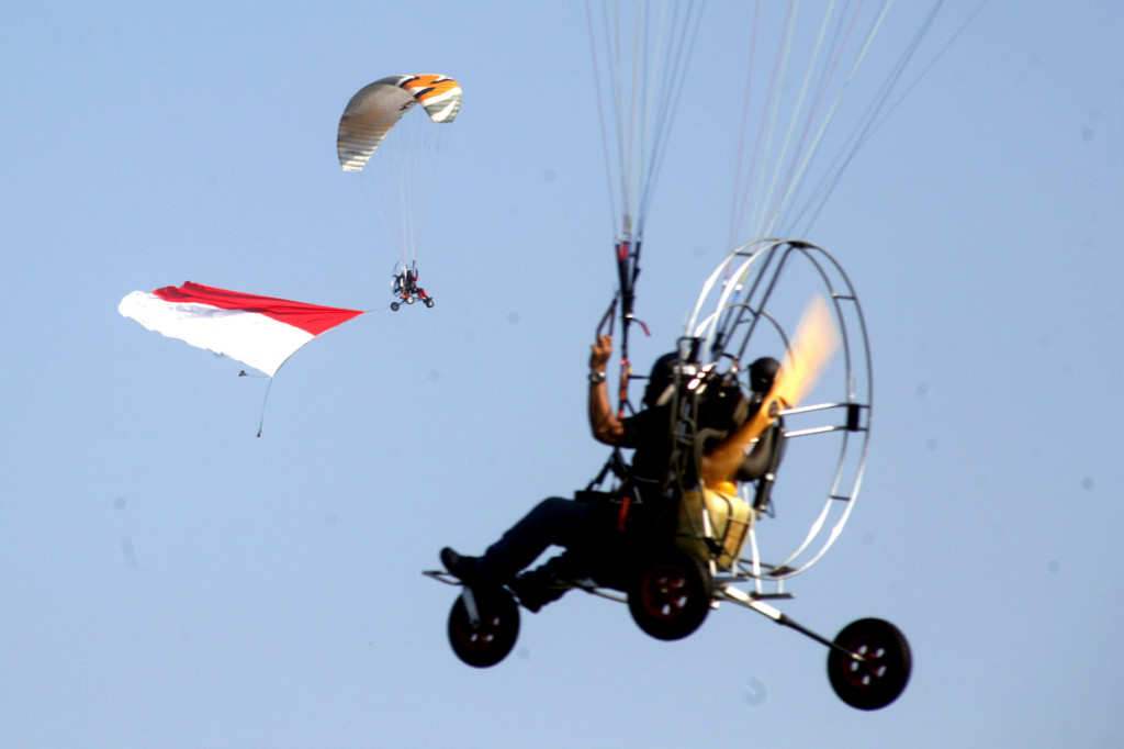 Pilot paramotor mengibarkan bendera Merah Putih di ketinggian dalam pemecahan rekor Museum Rekor Indonesia (MURI) di Lanud Atang Sendjaja (ATS), Kabupaten Bogor, Jawa Barat. 
