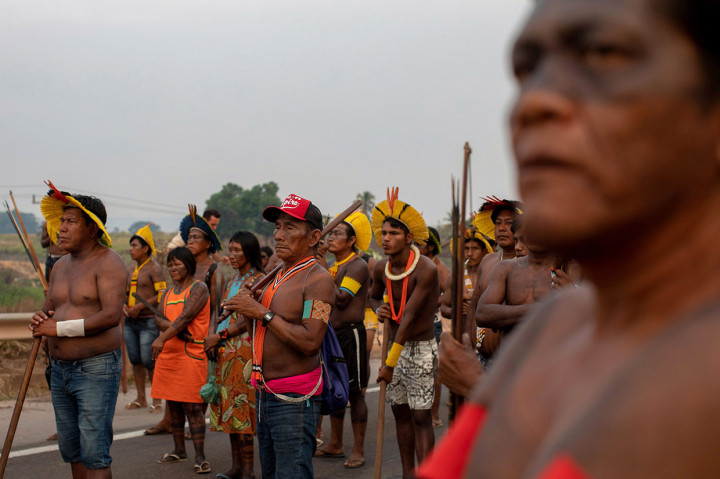 Mengacungkan busur dan mengenakan hiasan kepala bulu tradisional dan cat tubuh, puluhan pengunjuk rasa dari kelompok etnis Kayapo Mekranoti tersebut telah memblokade jalan raya BR-163 yang melalui hutan hujan Amazon sejak Senin, 17 Agustus 2020 pagi.