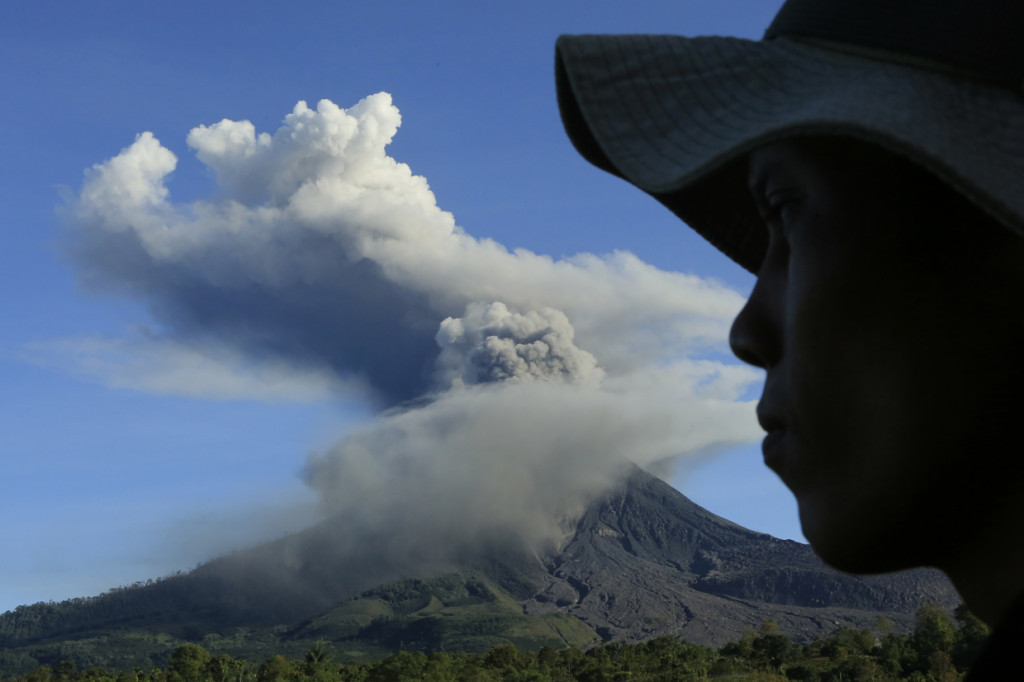 Warga mengamati Gunung Sinabung yang menyemburkan material vulkanik saat erupsi di Desa Tiga Pancur, Karo.