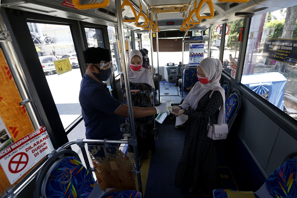 Awak bus angkutan massal Trans Koetaraja memberikan cairan antiseptik pembersih tangan (hand sanitizer) pada penumpang di Banda Aceh, Aceh.