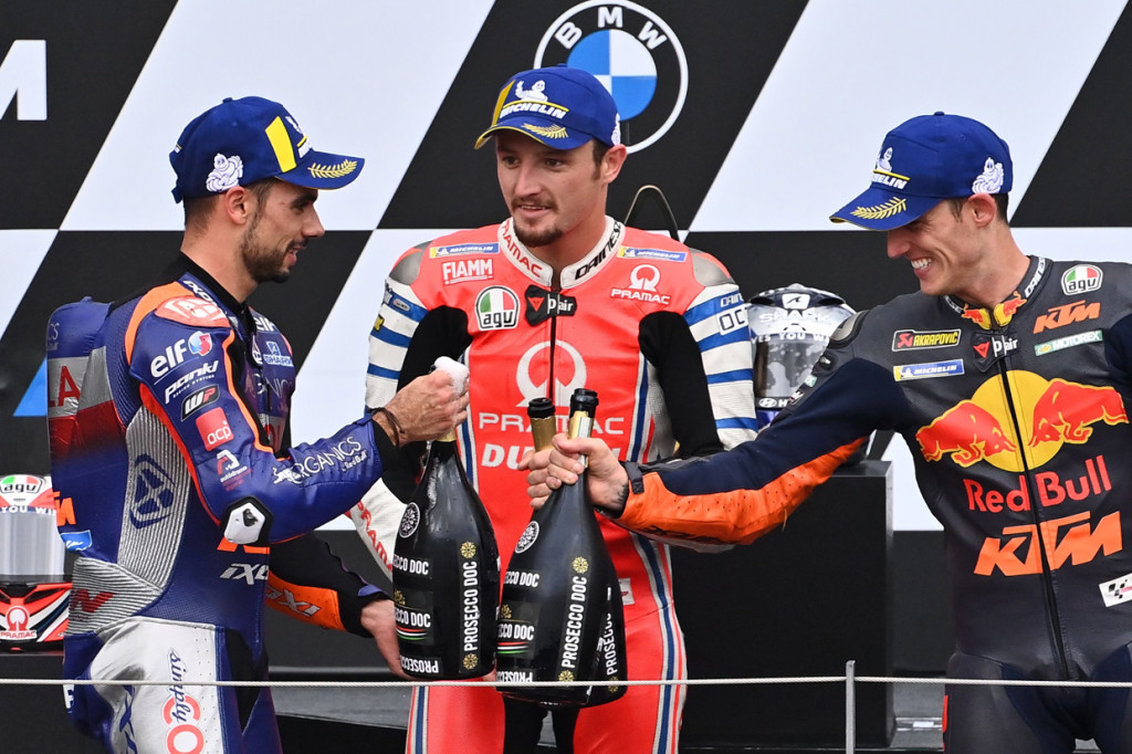 Miguel Oliveira berdiri di podium juara ditemani oleh Jack Miller dan Pol Espargaro.