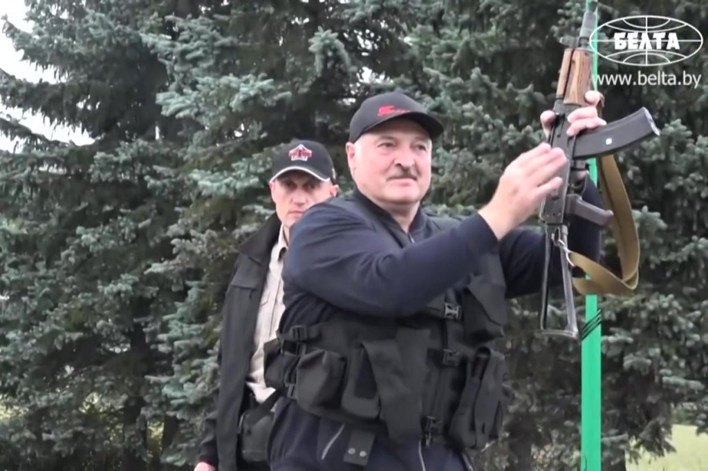 Lukashenko turun memegang senapan otomatis jenis Kalashnikov.