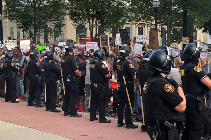Sekitar dua lusin petugas Sheriff Kenosha County berdiri di depan gedung pengadilan ketika para pengunjuk rasa di seberang jalan menyerukan keadilan rasial. Sementara helikopter berputar-putar di atas kepala serta petugas terlihat ditempatkan di atap gedung pengadilan.