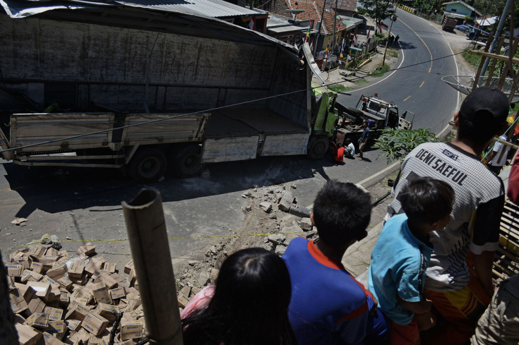 Warga melihat proses evakuasi truk pengangkut susu kemasan yang terguling di Nagreg, Kabupaten Bandung, Jawa Barat.