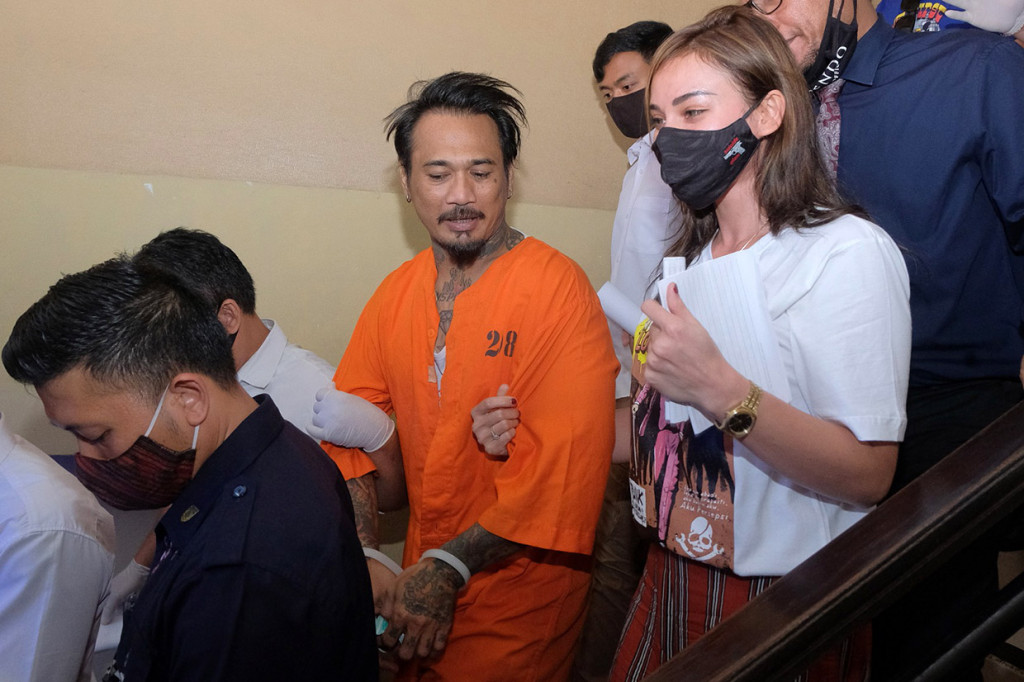 Polisi menggiring drummer grup musik Superman is Dead (SID) I Gede Ari Astina alias Jerinx (tengah) yang didampingi istrinya Nora Alexandra (kanan) usai pelimpahan berkas perkara di Direktorat Reserse Kriminal Khusus (Ditreskrimsus) Polda Bali, Denpasar, Bali, Kamis, 27 Agustus 2020. 