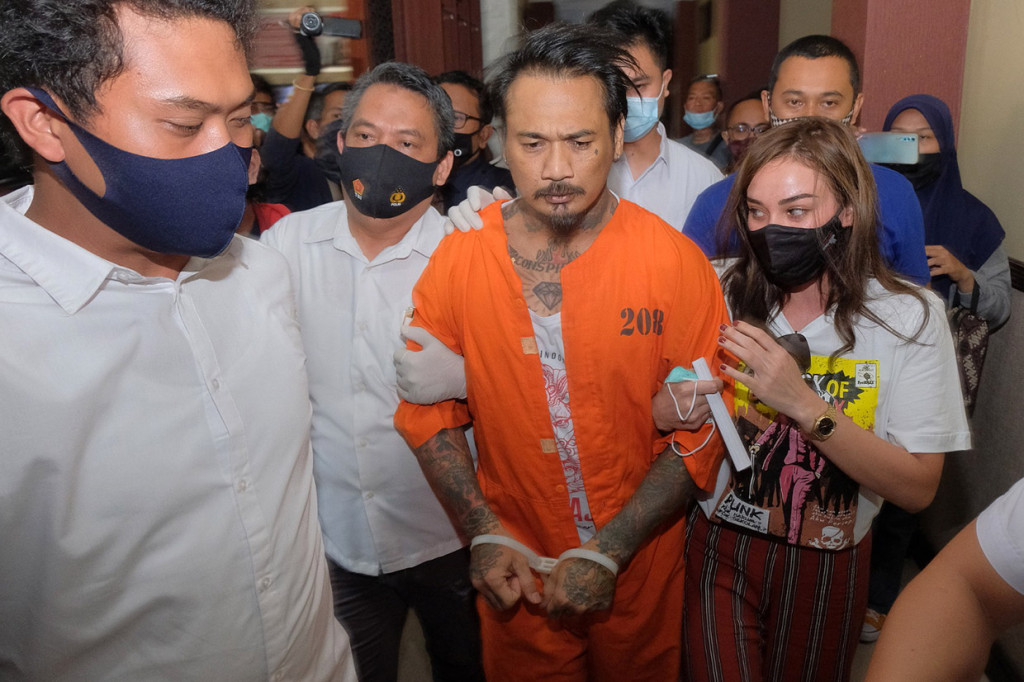 Polisi menggiring drummer grup musik Superman is Dead (SID) I Gede Ari Astina alias Jerinx (tengah) yang didampingi istrinya Nora Alexandra (kanan) usai pelimpahan berkas perkara di Direktorat Reserse Kriminal Khusus (Ditreskrimsus) Polda Bali, Denpasar, Bali, Kamis, 27 Agustus 2020. 