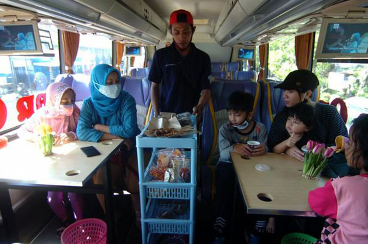 Pelayan menawarkan makanan dan minuman kepada pengunjung 'angkringan on the bus' di Pemalang, Jawa Tengah, Jumat, 28 Agustus 2020.