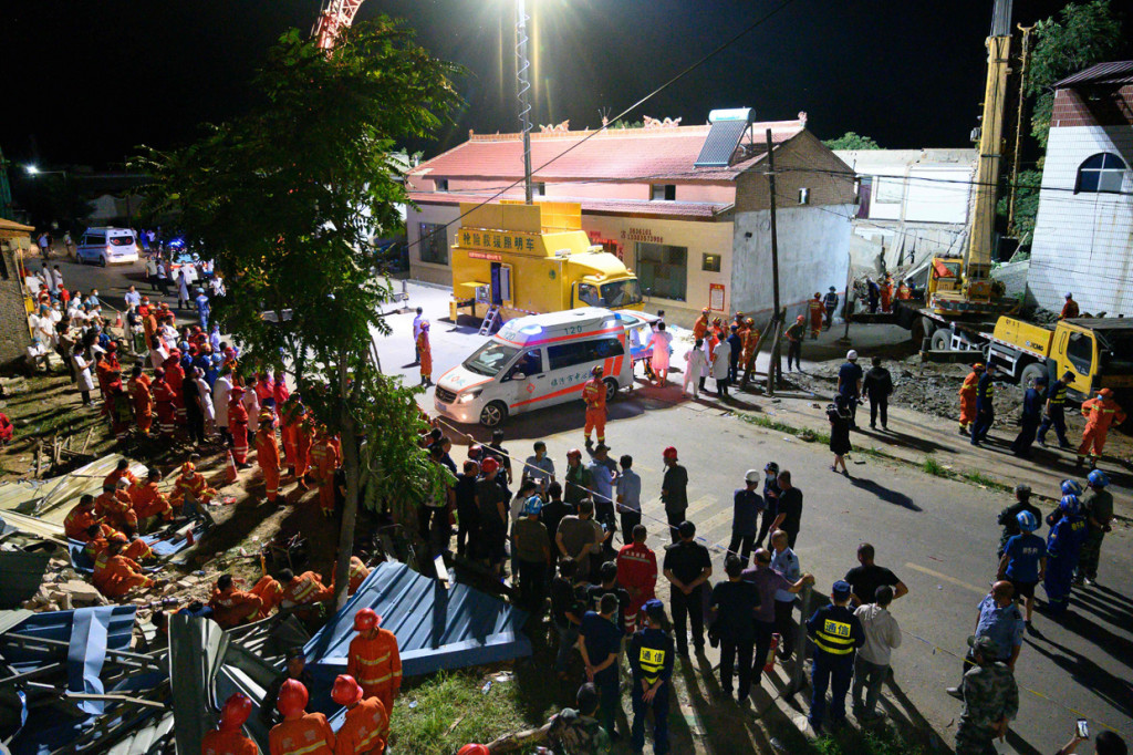 Tim penyelamat dengan pakaian oranye terus menyisir reruntuhan yang hancur saat sebuah lukisan masih tergantung di salah satu dari sedikit dinding yang masih utuh. Tujuh ratus orang terlibat dalam operasi penyelamatan itu.