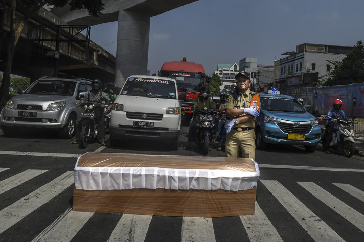 Camat Kecamatan Cilandak Mundari berpose dengan latar depan peti jenazah saat melakukan kampanye bahaya Covid-19 di Jakarta.