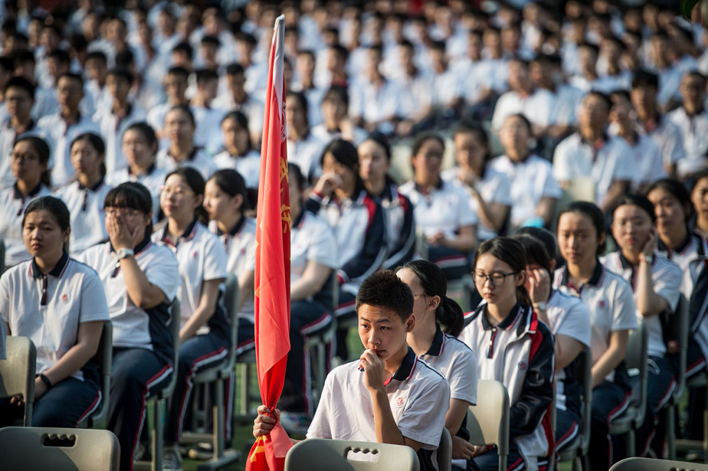 Media pemerintah menyiarkan gambar ribuan siswa yang mengibarkan bendera Tiongkok - rutinitas harian di semua sekolah umum - meskipun ada peringatan untuk menghindari pertemuan massal. 