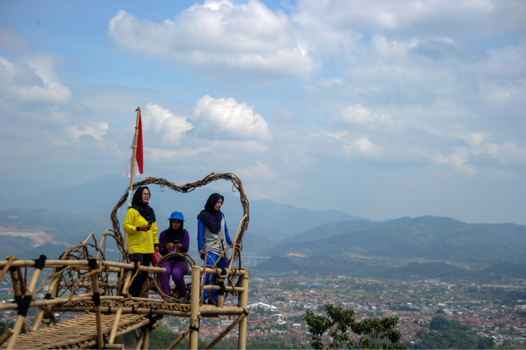 Wisatawan berswafoto dengan latar Kota Sumedang, di Puncak Gunung Pangadegan, Desa Rancamulya, Kabupaten Sumedang, Jawa Barat.