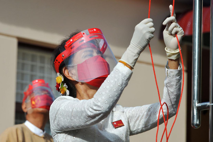 Mengenakan masker wajah berwarna merah, face shield, dan sarung tangan karet, Suu Kyi Selasa pagi mengibarkan bendera National League for Democracy (NLD) - dengan simbol merak tarung - di dalam sebuah upacara kecil kantor partai di ibu kota, Naypyidaw.