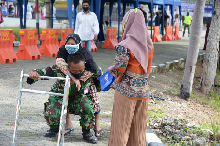 Personil TNI membantu menggendong seorang warga lanjut usia seusai menjalani rapid test masal, di komplek Kampus Politeknik Indonesia Venezuela, Desa Cot Suruy, Kecamatan Ingin Jaya, Kabupaten Aceh Besar.