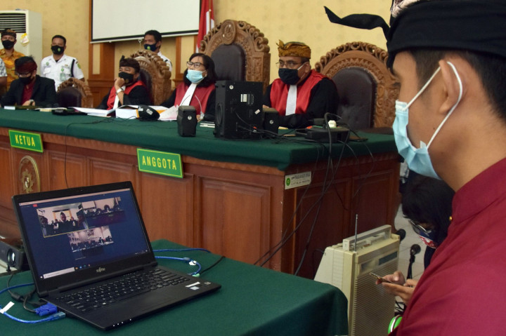 Petugas memantau jalannya sidang perdana drummer grup musik Superman is Dead (SID) I Gede Ari Astina alias Jerinx dalam kasus ujaran kebencian dan pencemaran nama baik yang digelar secara daring di Pengadilan Negeri Denpasar, Bali.