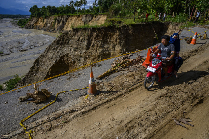 Pengendara sepeda motor melintasi jalan yang amblas akibat abrasi sungai di Desa Simoro, Kecamatan Gumbassa, Kabupaten Sigi, Sulawesi Tengah.
