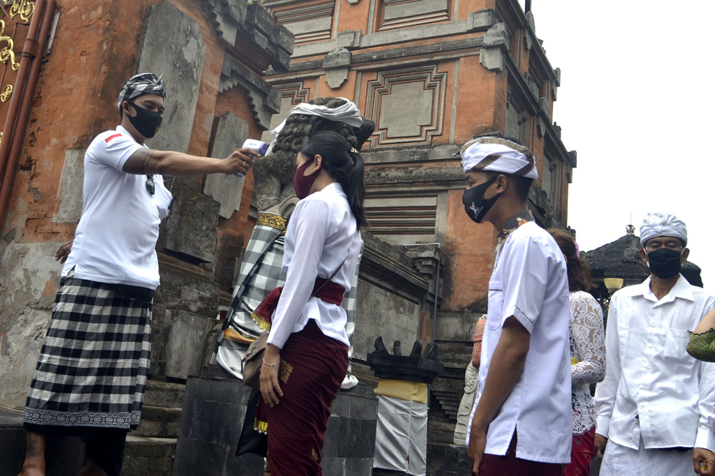 Pecalang atau petugas pengamanan adat Bali memeriksa suhu tubuh umat Hindu yang akan bersembahyang saat Hari Raya Galungan di Pura Jagatnatha, Denpasar.