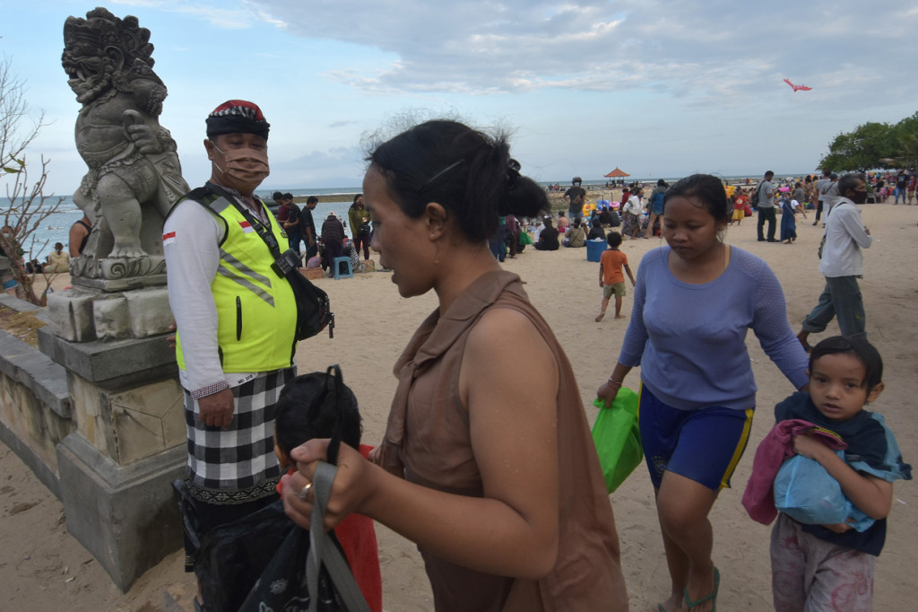 Pecalang atau petugas keamanan desa adat di Bali menegur warga yang melepas masker saat liburan Hari Raya Galungan di Pantai Sanur, Denpasar, Bali.