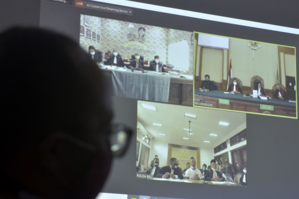 Petugas memantau pelaksanaan sidang lanjutan secara daring terhadap drummer Superman is Dead I Gede Ari Astina alias Jerinx di Pengadilan Negeri Denpasar, Bali. Pengadilan Negeri Denpasar menyelenggarakan sidang kedua kasus dugaan ujaran kebencian dan pencemaran nama baik yang dilaporkan Ikatan Dokter Indonesia (IDI) Bali tersebut dengan agenda pembacaan dakwaan kembali setelah pada sidang perdana lalu terdakwa Jerinx berserta kuasa hukumnya melakukan aksi 