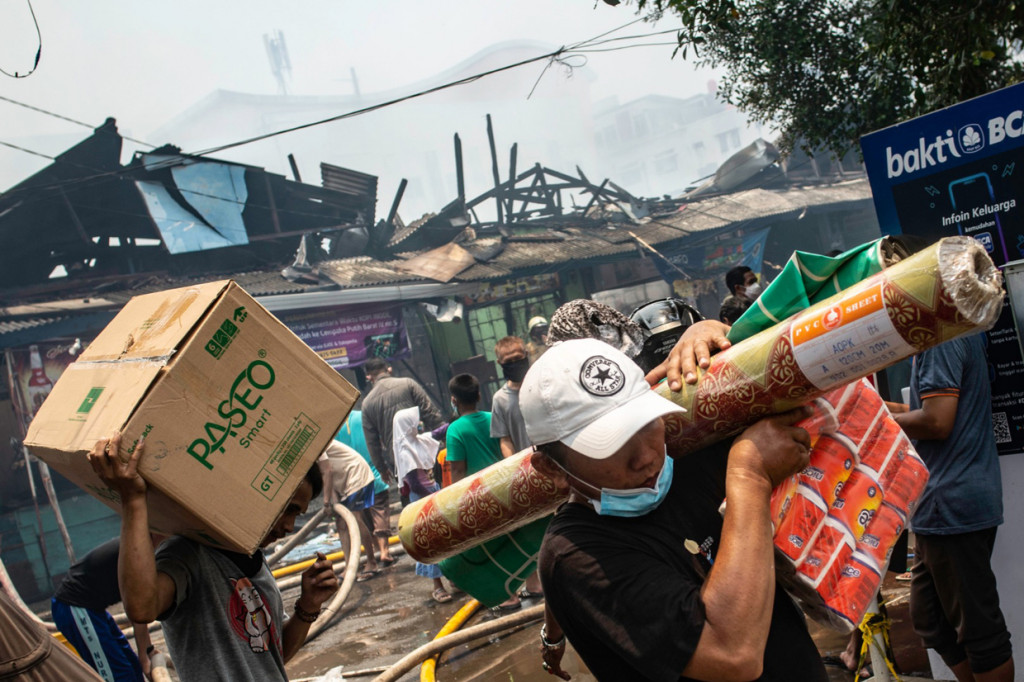 Pedagang mengevakuasi barang dagangannya saat terjadi kebakaran di Pasar Cempaka Putih, Jakarta.