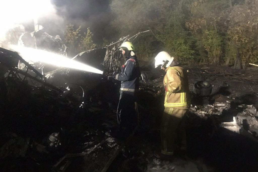 Petugas pemadam kebakaran melakukan pembasahan di lokasi kecelakaan pesawat militer Antonov-26 di dekat pangkalan udara militer Chuhuiv, 30 kilometer tenggara dari Kharkiv, Ukraina, Jumat, 25 September 2020 waktu setempat.