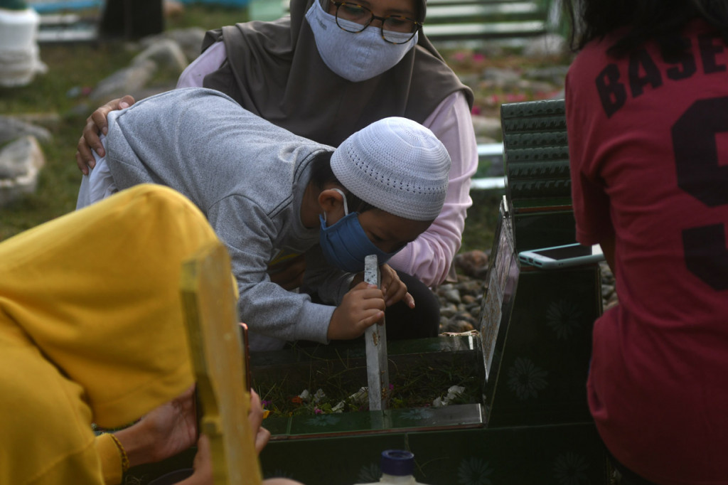Seorang anak mencium nisan makam keluarganya saat berziarah ke makam massal korban bencana gempa, tsunami, dan likuefaksi di Kelurahan Poboya, Palu, Sulawesi Tengah. ANTARA Foto/Mohamad Hamzah