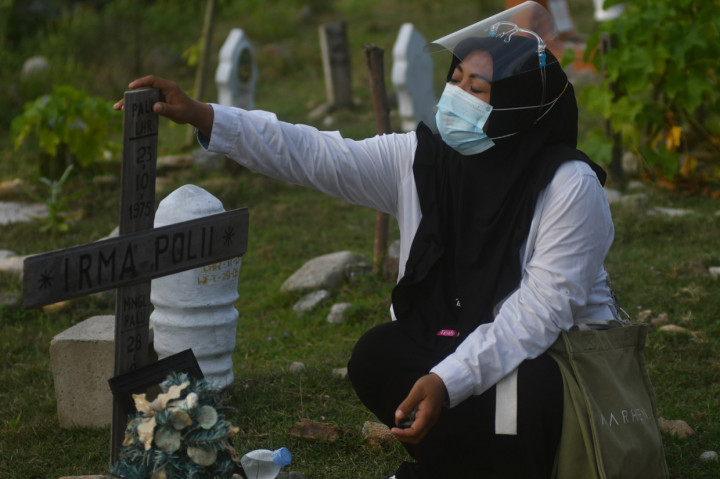 Seorang warga memegang nisan makam sahabatnya saat berziarah ke makam massal korban bencana gempa, tsunami, dan likuefaksi di Kelurahan Poboya, Palu, Sulawesi Tengah. ANTARA Foto/Mohamad Hamzah