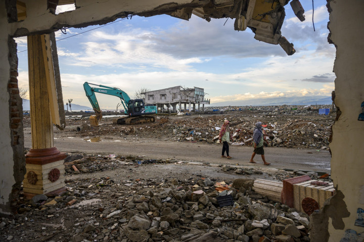 Warga melintas di depan puing rumah yang hancur akibat tsunami dan belum dirobohkan di Palu, Sulawesi tengah. Setelah dua tahun bencana, sejumlah bangunan yang rusak belum dibersihkan. ANTARA Foto/Basri Marzuki