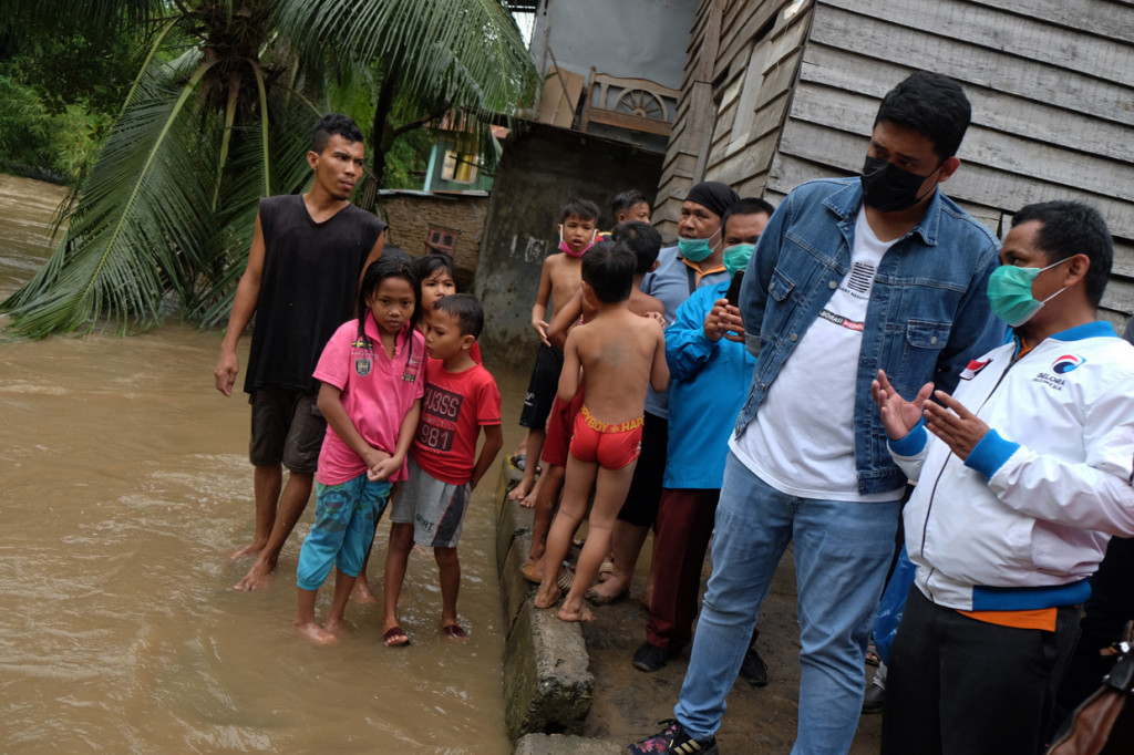 Calon Wali Kota Medan nomor urut dua Bobby Nasution (kedua kanan) berbincang dengan pengurus Partai Gelora saat meninjau lokasi banjir akibat meluapnya aliran Sungai Deli di Medan, Sumatera Utara.