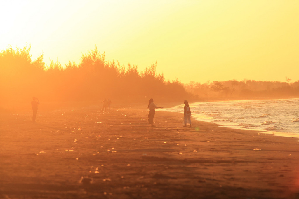 Pengunjung menikmati suasana matahari terbenam di Pantai Tiris, Pasekan, Indramayu, Jawa Barat.