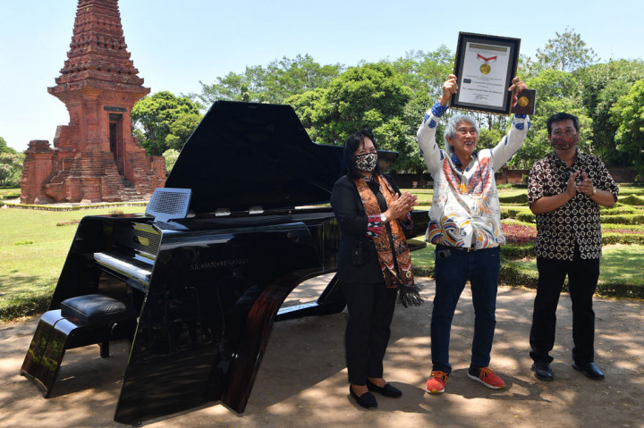 Presiden Direktur PT Saniharto Enggalhardjo Harsono Enggalhardjo (tengah) mengangkat piagam Museum Rekor Dunia Indonesia (MURI) untuk 'grand piano pertama buatan Indonesia' di Candi Gapura Bajang Ratu, Trowulan, Mojokerto, Jawa Timur, Sabtu, 3 Oktober 2020. 