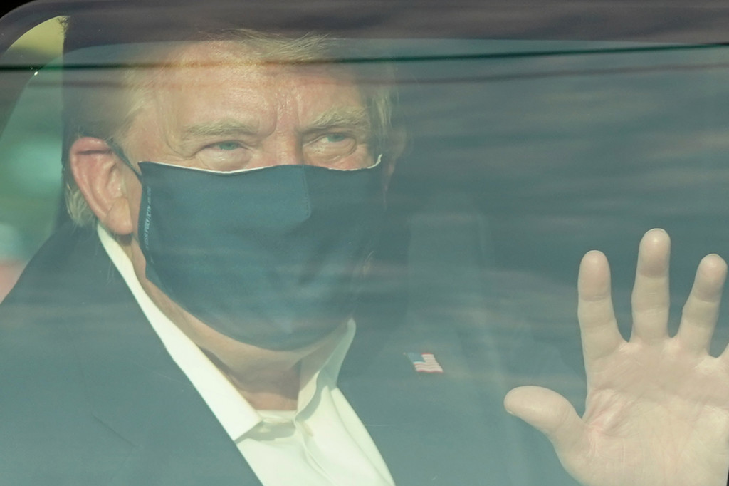 Presiden AS Donald Trump melambaikan tangan dari dalam mobil ke arah para pendukungnya di luar rumah sakit Walter Reed di Bethesda, Maryland.