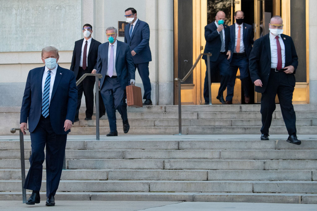 Mengenakan masker, Trump melangkah keluar dari Walter Reed National Military Medical Center, rumah sakit militer di Bethesda, Maryland.