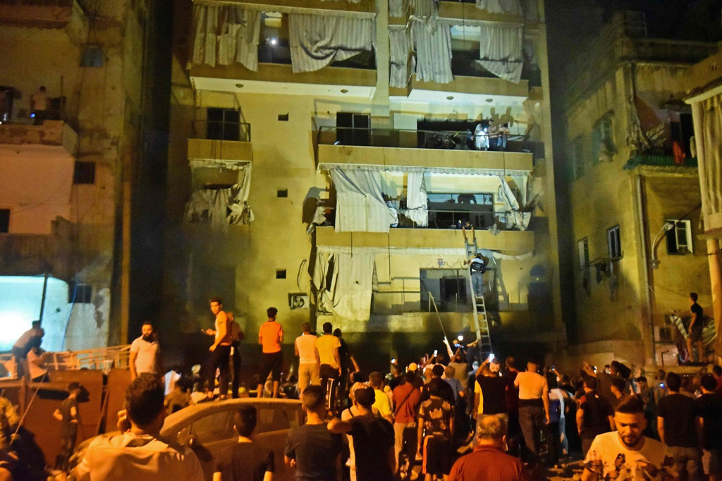 Petugas pemadam kebakaran yang menggunakan tangga bergerak untuk mengevakuasi orang-orang dari gedung-gedung di Distrik Tariq al-Jdide.