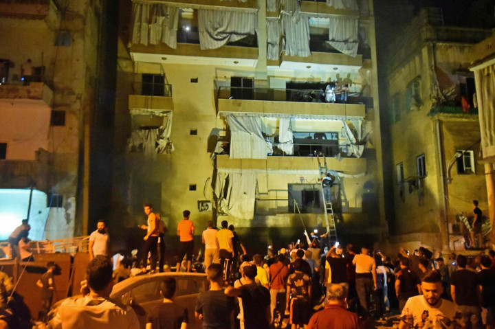 Petugas pemadam kebakaran yang menggunakan tangga bergerak untuk mengevakuasi orang-orang dari gedung-gedung di Distrik Tariq al-Jdide.