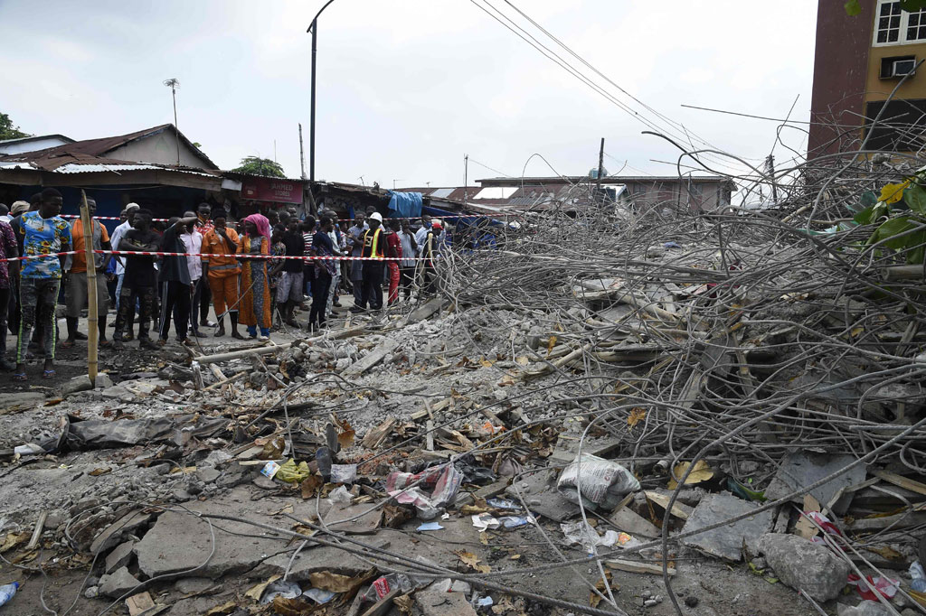 Warga melihat puing-puing bangunan tiga lantai yang runtuh di Lagos, Nigeria, Senin 12 Oktober 2020 waktu setempat.